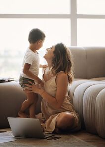 Picture of woman sitting on the floor with her standing toddler son