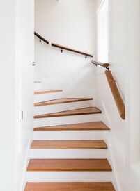 Picture of white staircase with wooden handrail inside of a home